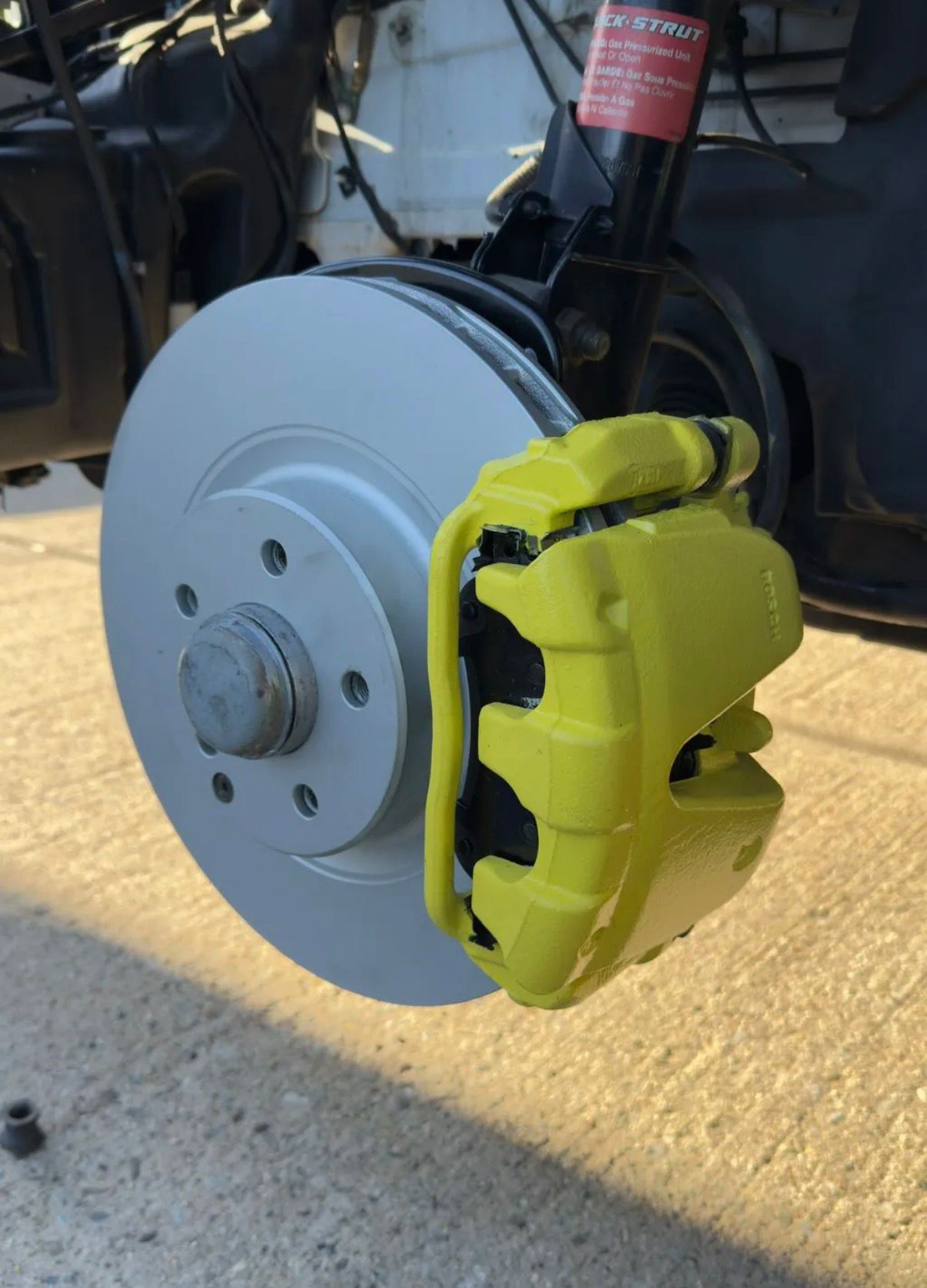 Front brake rotor with a freshly painted yellow-green caliper